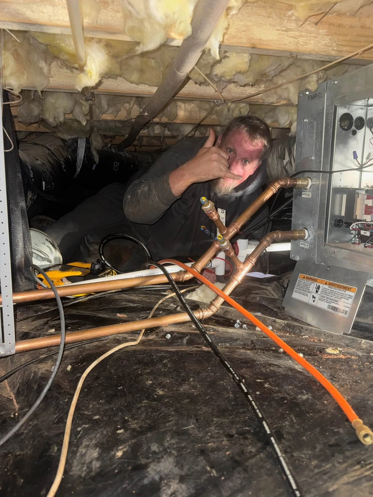 A Warren Mechanical technician working on an HVAC system at a real jobsite